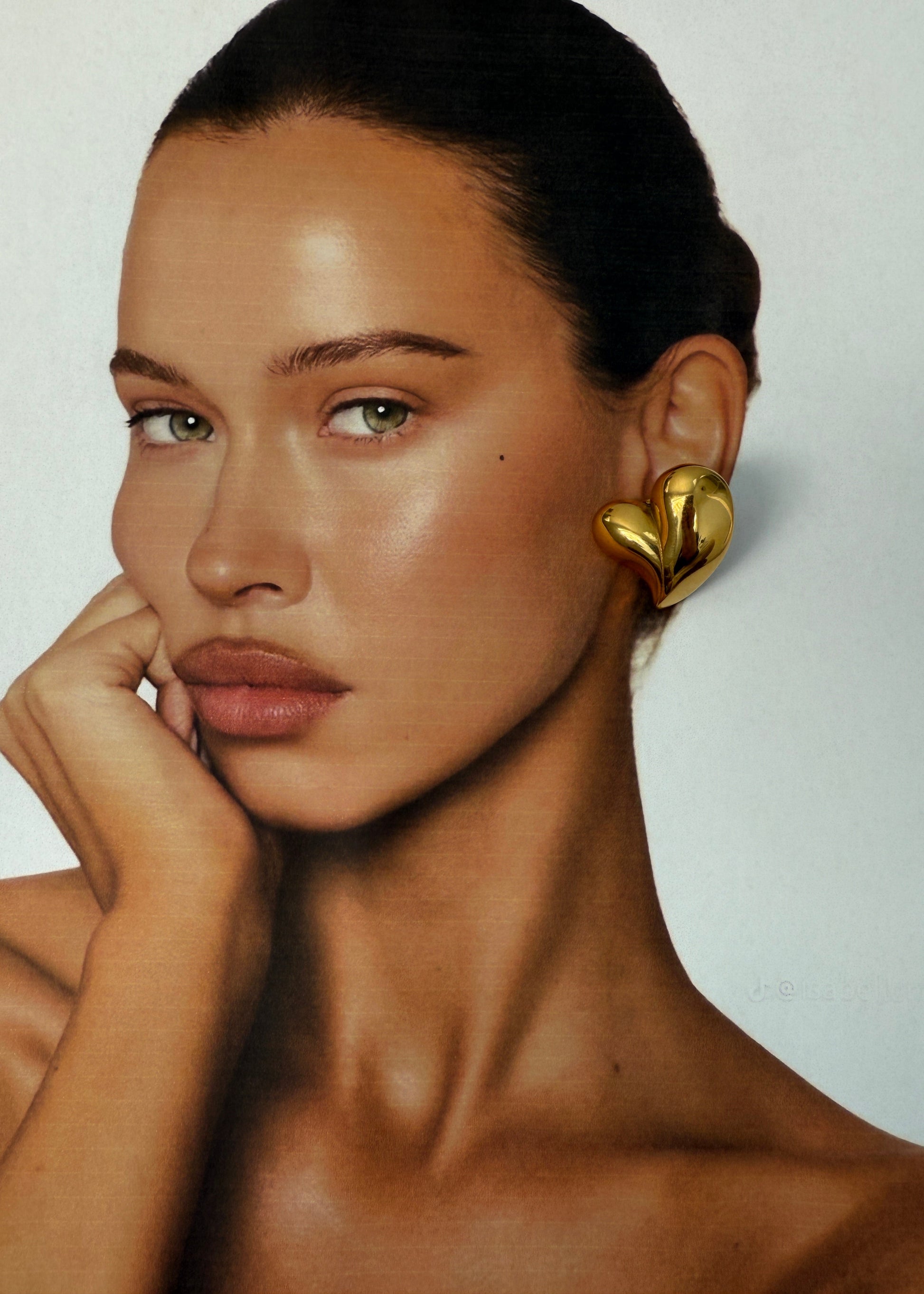 Woman wearing a gold earring with a plain background